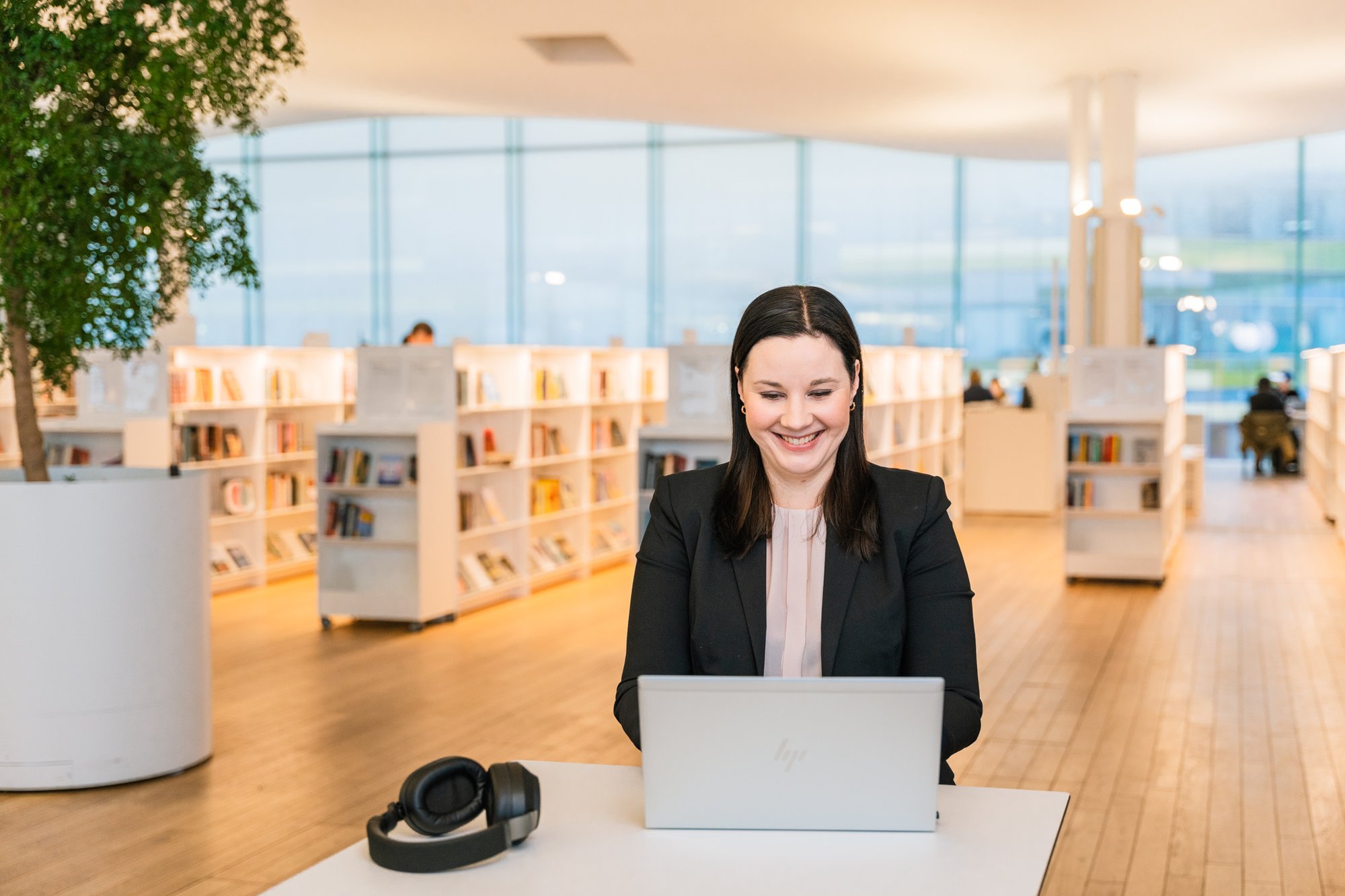 Kvinna sitter i ett bibliotek och arbetar framför en dator