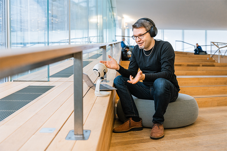 Man sitting on a stair recording a onlinelecture from the computer
