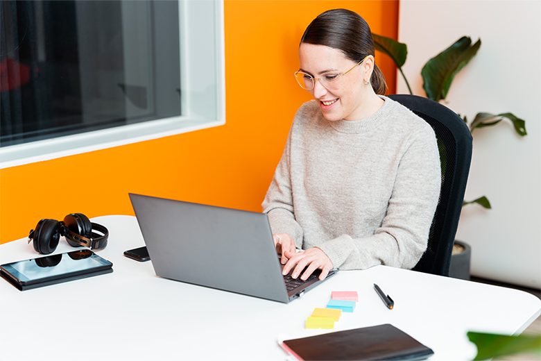 Kvinna sitter vid ett skrivbord och arbetar framför en dator