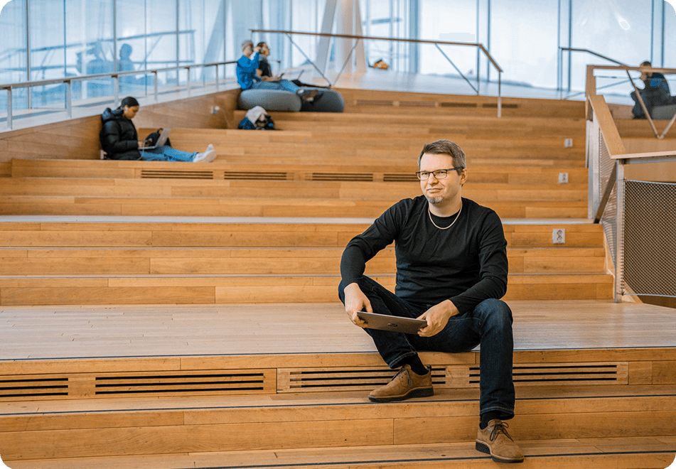 Flera personer sitter på en trappa i ett bibliotek och studerar 