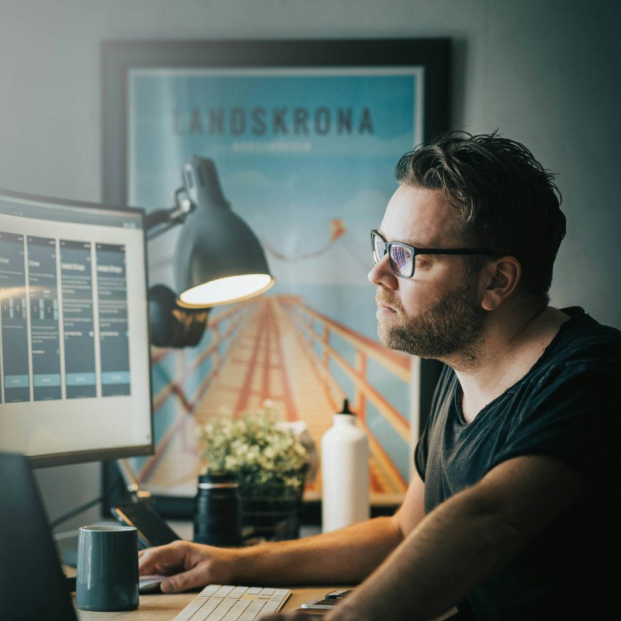 man i t-shirt och glasögon vid sin arbetsplats