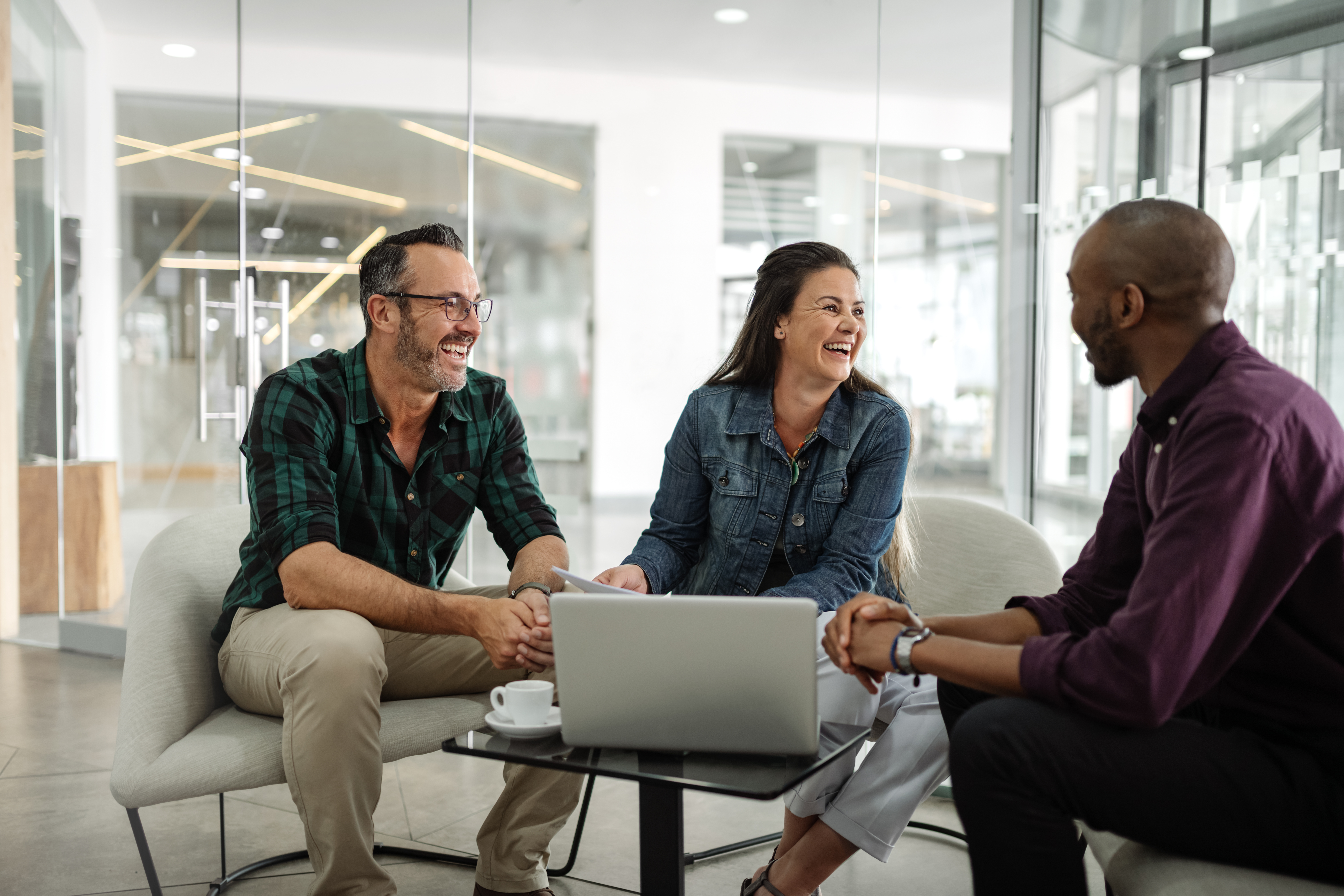 3 persons sitting at a table discussing and laughing